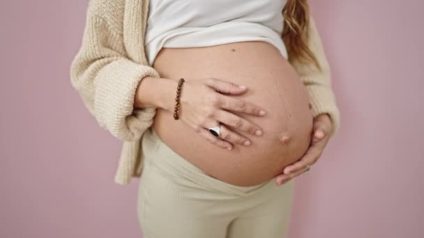 Nuori raskaana oleva nainen hierovat vatsa yli eristetty vaaleanpunainen tausta - Materiaali, video