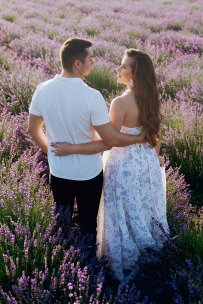 Krásný pár, kde dívka v elegantních šatech na levandulovém poli při západu slunce. - Fotografie, Obrázek