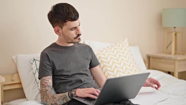 Giovane uomo ispanico utilizzando carta da lettura portatile in camera da letto - Filmati, video