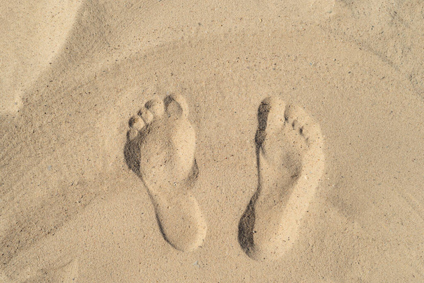 Textura fondo Huellas de pies humanos en la arena cerca del agua en la playa. - Foto, Imagen
