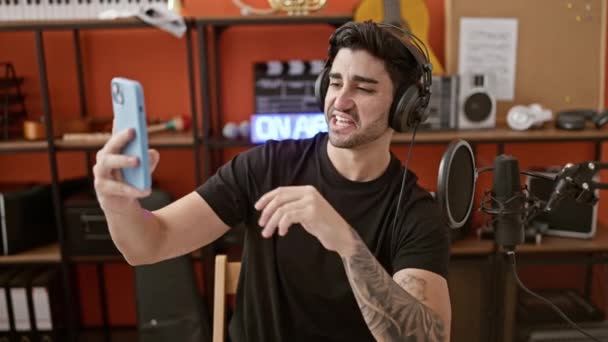 Молодий іспаномовний музикант знімає навушники з відеодзвінка в музичній студії - Кадри, відео