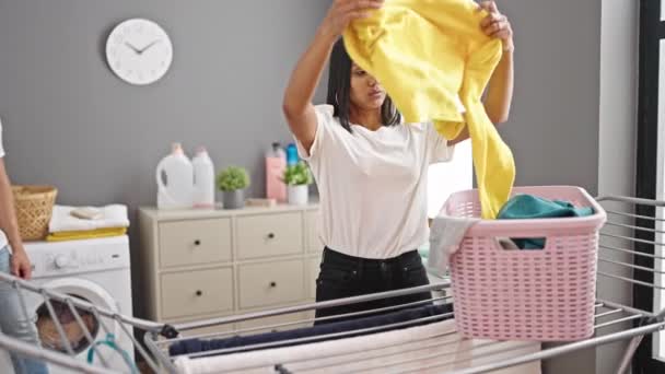 Férfi és nő lóg ruhák a ruhaszárító, míg a barátja használja okostelefon mosókonyhában - Felvétel, videó