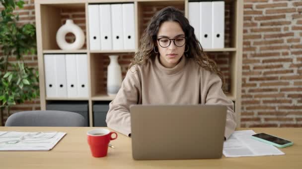 Młoda piękna latynoska kobieta biznes pracownik podkreślił za pomocą laptopa w biurze - Materiał filmowy, wideo