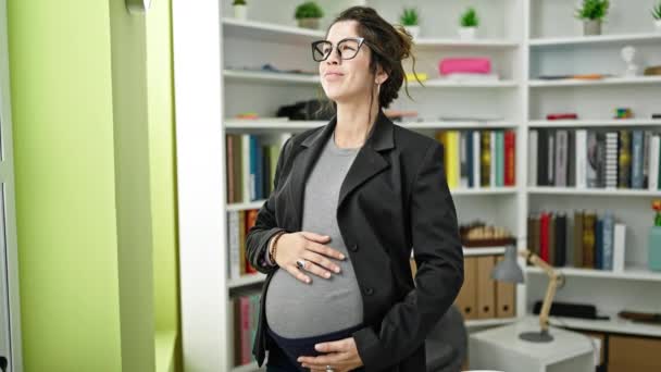 Молода вагітна жінка вчителька посміхається впевнено торкаючись живота в бібліотечному університеті
 - Кадри, відео