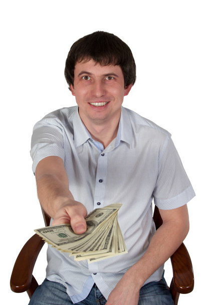 Businessman sitting on a chair holds out dollars - Photo, Image