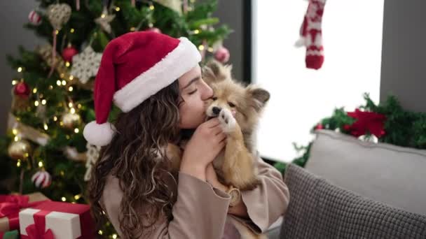 自宅でクリスマスを祝う自信を持って笑顔の犬を持つ若いヒスパニックの女性 - 映像、動画