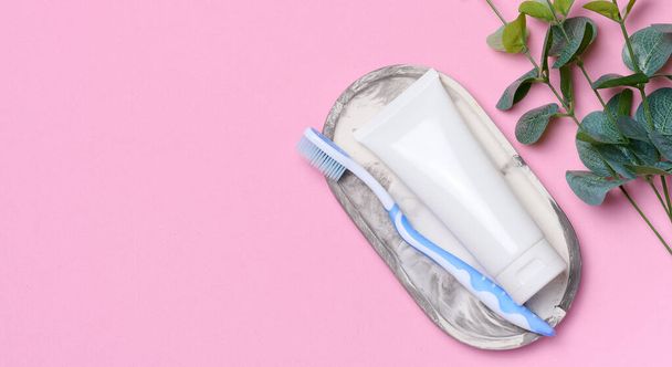 Tubo di dentifricio in plastica bianca e spazzolino da denti su fondo rosa. Copia spazio - Foto, immagini