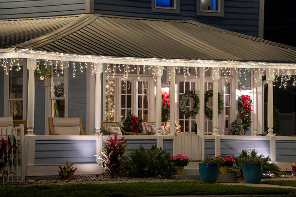 Яскраво освітлені різдвяні прикраси на передньому дворі ганку сімейного будинку Флориди. Зовнішній декор для зимових канікул
. - Фото, зображення
