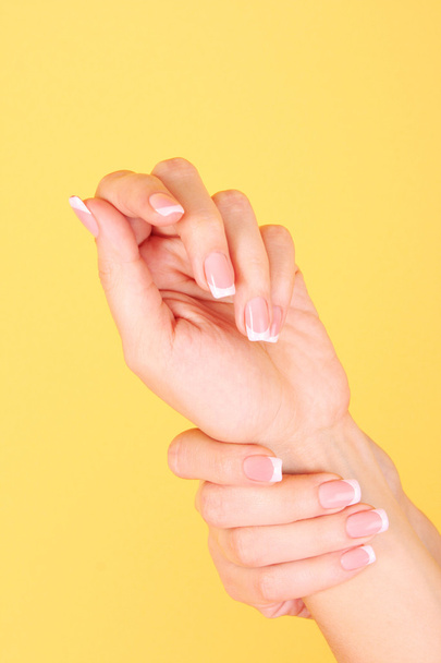 Beautiful woman hands with french manicure on yellow background - Foto, Imagem