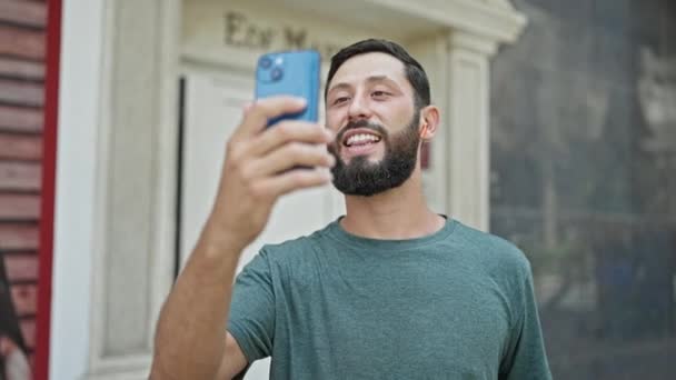 Nuori latino mies hymyilee luottavainen ottaa videopuhelu kadulla - Materiaali, video