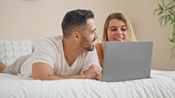 Man and woman couple lying on bed together using laptop at bedroom - Footage, Video