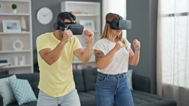 Man and woman couple playing boxing game using virtual reality glasses at home - Footage, Video