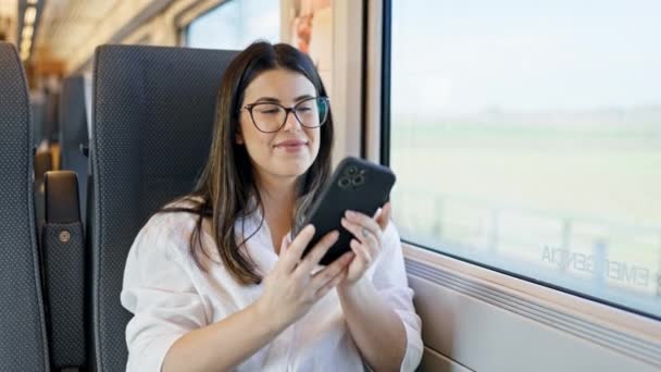 Genç ve güzel İspanyol kadın gülümsüyor tren istasyonunda oturan akıllı telefonuyla selfie çekiyor. - Video, Çekim