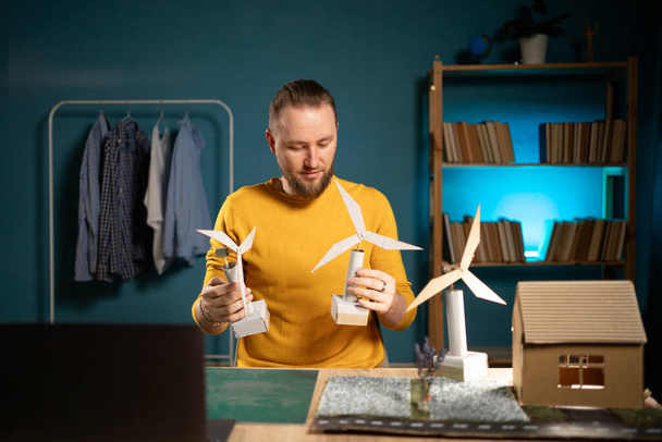 Ein Mann, der abends zu Hause ein kreatives 3D-Windkraftprojekt entwirft. Alternatives Energiekonzept. Kopierraum - Foto, Bild