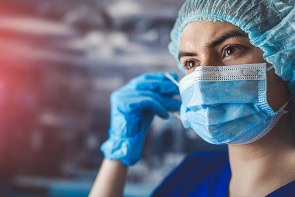 Enfermeira jovem cansada ou médico tirar a máscara após o turno de trabalho na clínica médica. - Foto, Imagem