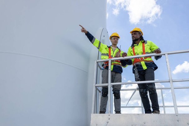 Technik budowy turbin wiatrowych męski zespół pracujący na budowie serwisu serwisowego. Generator energii ekologicznej dla pracowników zatrudnionych zgodnie z zasadami zrównoważonego rozwoju. - Zdjęcie, obraz