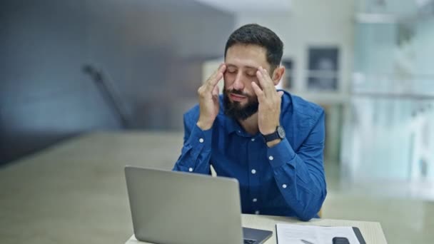 Junger hispanischer Geschäftsmann leidet unter Kopfschmerzen bei der Arbeit im Büro - Filmmaterial, Video