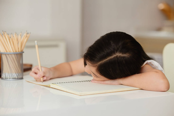 παιδί κορίτσι τεμπέλης εκπαίδευση στο σπίτι αισθάνονται βαρετό κάθεται το κεφάλι κάτω κάνει την εργασία - Φωτογραφία, εικόνα