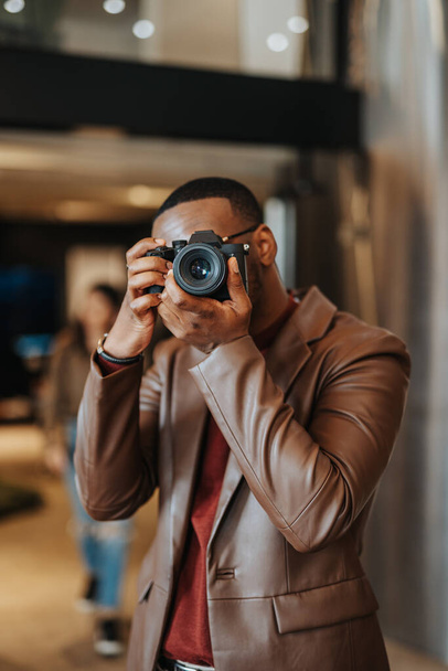 O jovem fotógrafo estava filmando com uma câmera digital SLR, capturando imagens impressionantes do edifício moderno - Foto, Imagem