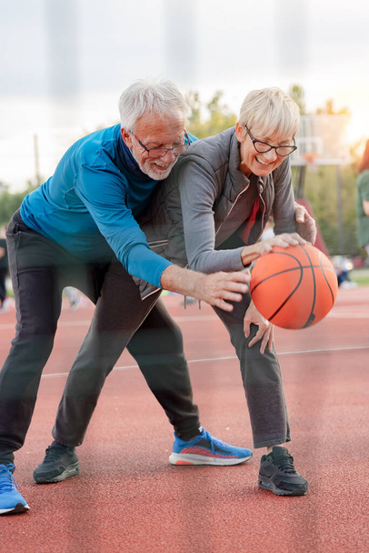 idős nő és érett férfi kosárlabdázik a parkban - Fotó, kép