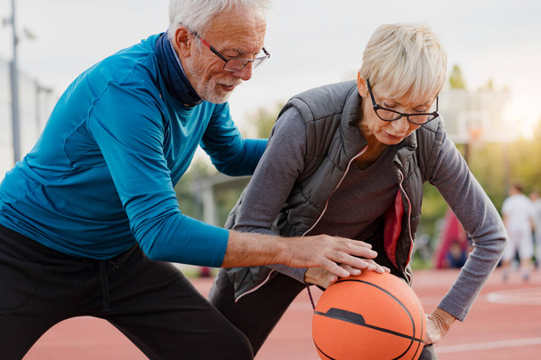 senior femme et mature homme jouer basket dans le parc - Photo, image