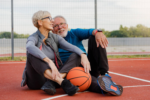 senior woman and mature man playing basketball in the park - Foto, imagen