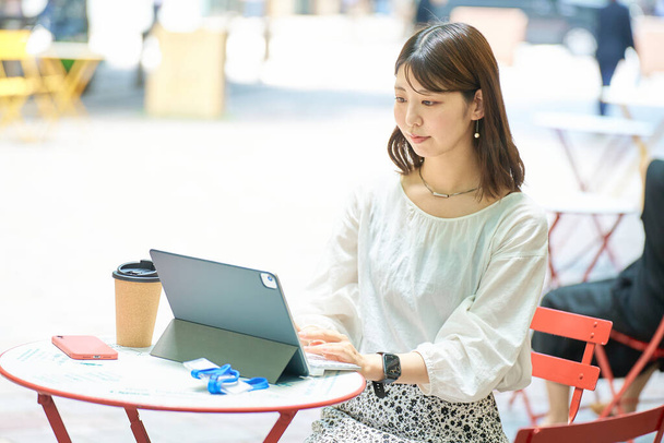 Eine Frau, die an schönen Tagen im Freien einen PC bedient - Foto, Bild