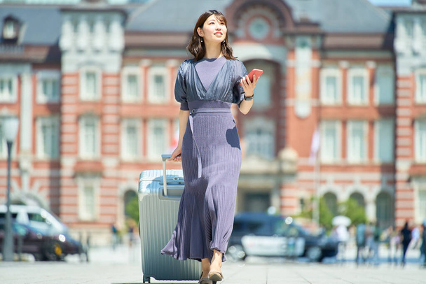 Eine Frau, die an schönen Tagen mit einem Koffer durch die Stadt läuft - Foto, Bild