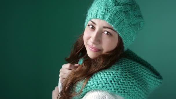 Smiling girl in a turquoise knitted hat posing on camera - Záběry, video