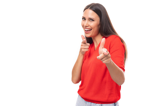 若い親切な魅力的なブルネットの女性は白い背景に甘く微笑む赤いTシャツを着て. - 写真・画像