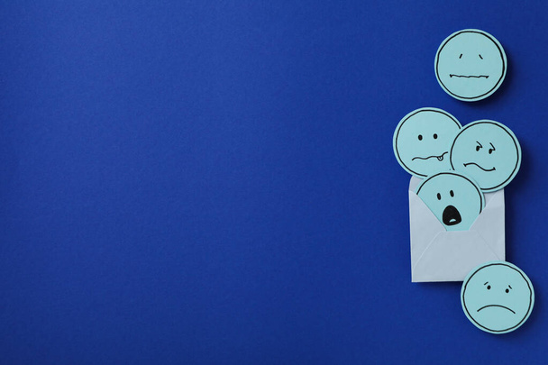 Busta con emoji triste su sfondo blu, spazio per testo - Foto, immagini