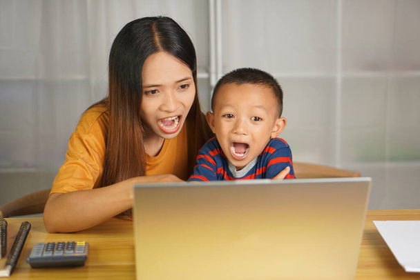 moeder en zoon kijken films op de computer thuis tafel - Foto, afbeelding