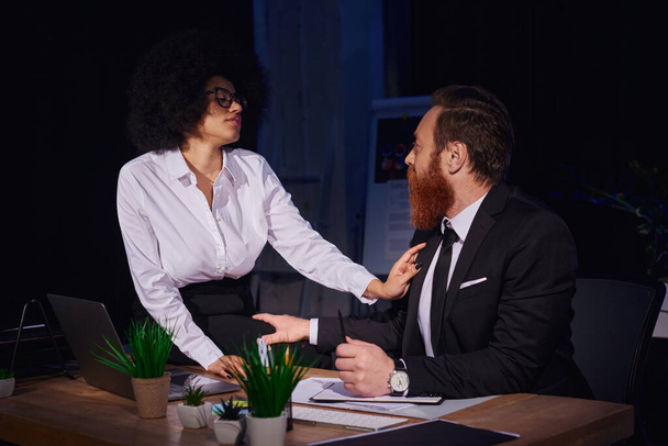 Африканская американская бизнесвумен соблазняет бородатого мужчину на рабочем месте, любовную интрижку в ночном офисе - Фото, изображение