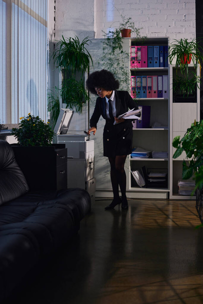 mulher afro-americana em elegante formal desgaste cópia documentos enquanto trabalhava no escritório à noite - Foto, Imagem