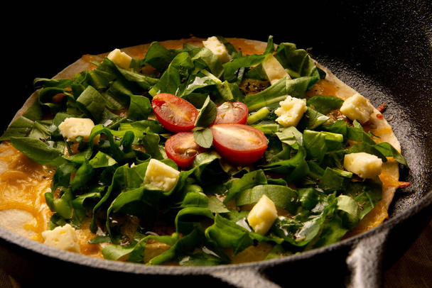 Сырная Пицца Аругула с вишневыми помидорами в чугунной сковороде с обрезанным видом спереди - Фото, изображение
