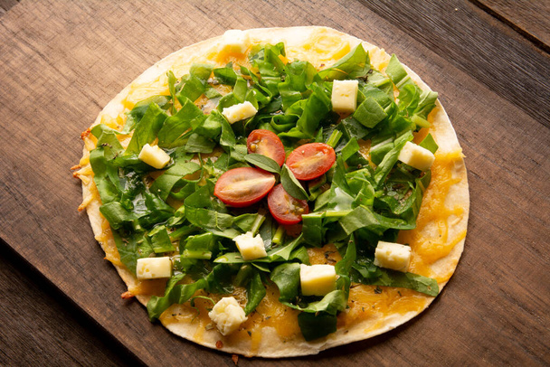 Arugula homemade pizza pan with cheese and cherry tomatoes above a wooden table in tow view - Photo, Image