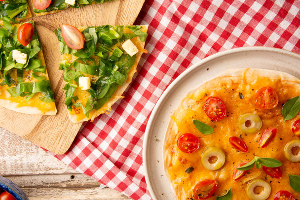 Pizze servite con pomodori, rucola e formaggio in un piatto di ceramica fatto a mano in vista dall'alto - Foto, immagini
