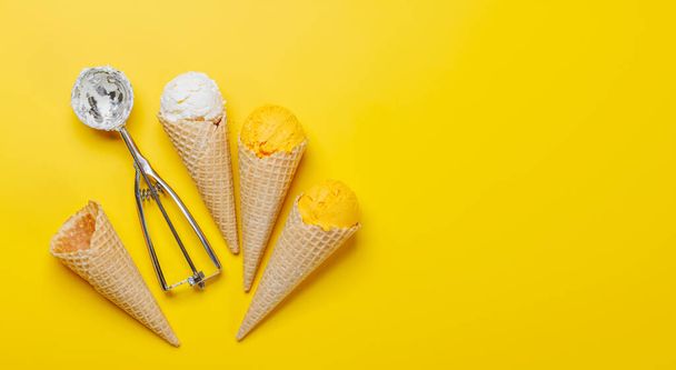Surtido de sabores de helado en deliciosos conos de gofres, un regalo para todos los papilas gustativas. Sobre fondo amarillo con espacio de copia, plano - Foto, imagen