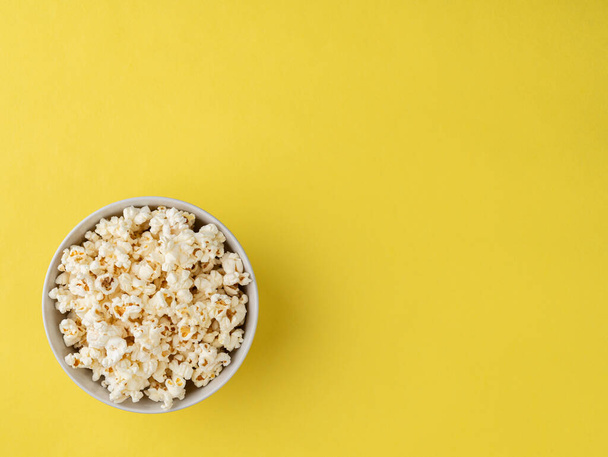 Popcorn in einer Schüssel über gelbem Hintergrund mit Kopierraum. - Foto, Bild