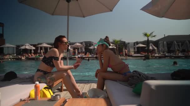Zwei entzückende Mädchen unterhalten sich und genießen ihre Zeit am Pool. Hochwertiges 4k Filmmaterial - Filmmaterial, Video