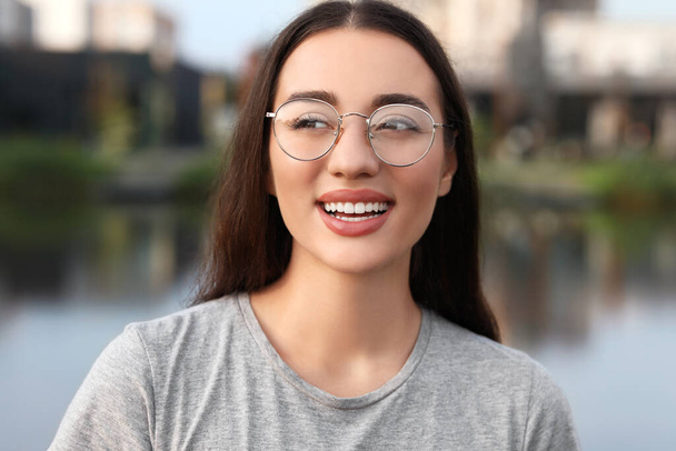 Portrait of beautiful woman in glasses outdoors. Attractive lady smiling and posing for camera - Photo, image