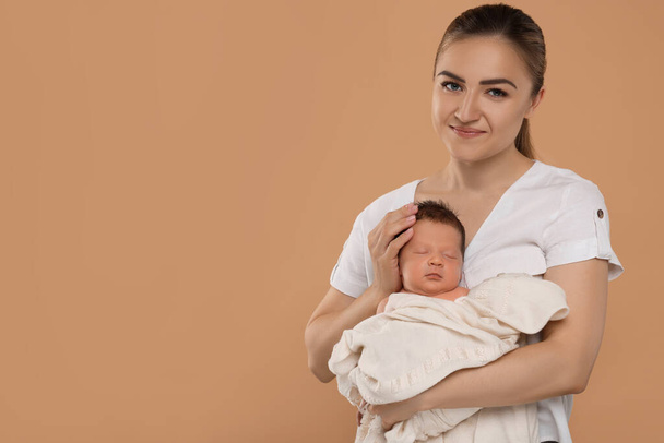 Mother with her cute newborn baby on beige background. Space for text - Foto, afbeelding