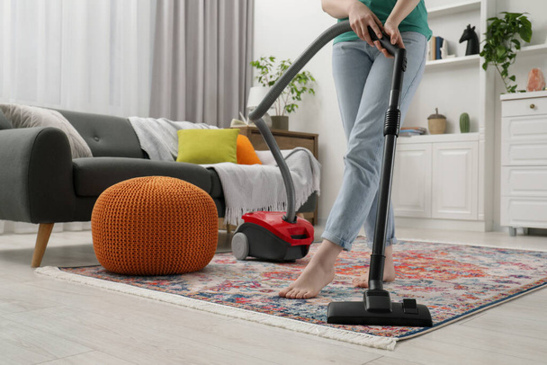 Woman cleaning carpet with vacuum cleaner at home, closeup - Foto, afbeelding
