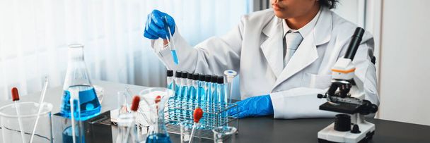 Wetenschapper voert chemisch experiment in medisch laboratorium, zorgvuldig druppel precieze hoeveelheid vloeistof uit pipet in reageerbuis voor vaccin drug of antibiotica ontwikkeling. Neoterisch - Foto, afbeelding