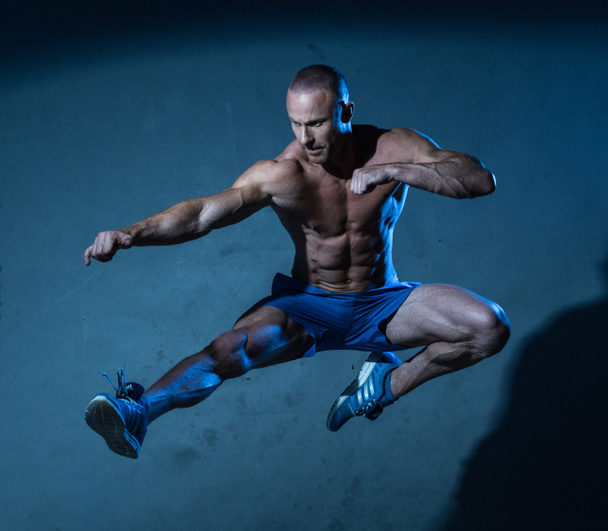 Sportlicher junger Mann in fliegender Kampfkunst-Pose - Foto, Bild