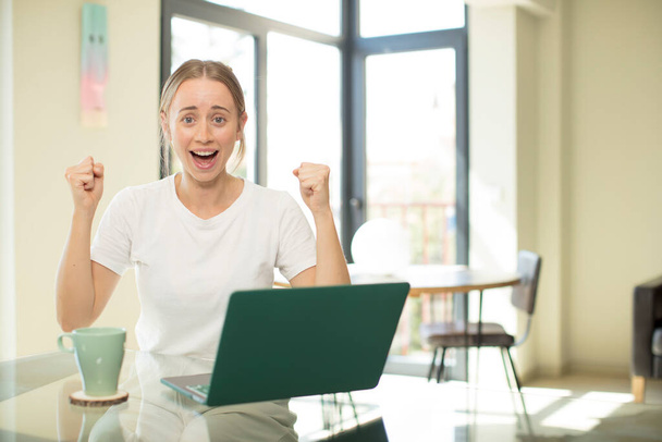 caucasian pretty woman with a laptop shouting aggressively with an angry expression or with fists clenched celebrating success - Foto, immagini