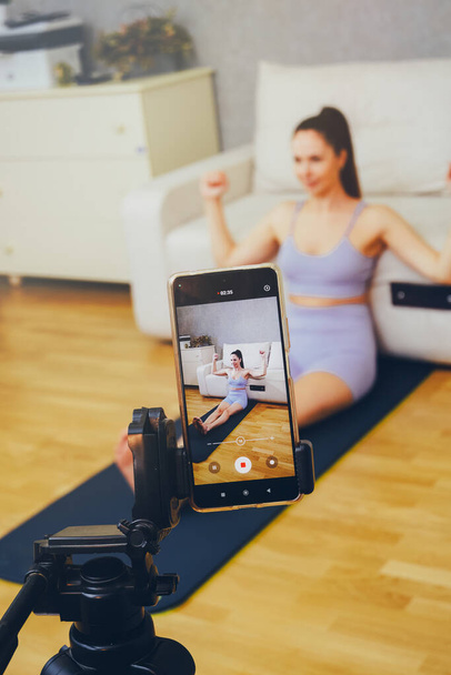 Una chica bloguera de fitness graba un entrenamiento o transmite en vivo en Internet. - Foto, imagen