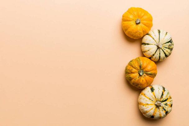 Composizione autunnale di piccole zucche arancioni su sfondo colorato del tavolo. Autunno, Halloween e il Ringraziamento concetto. Autunno fotografia laica piatta. Vista dall'alto vith spazio di copia. - Foto, immagini