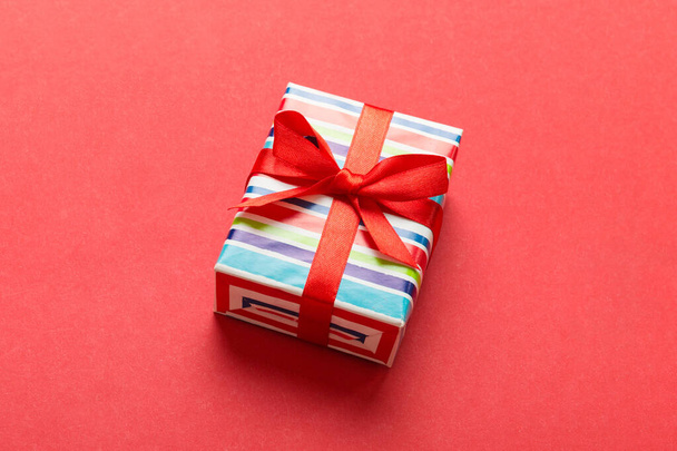 Verhüllte Weihnachten oder andere Feiertage handgemachtes Geschenk in Papier mit farbigem Band. Geschenkschachtel, Geschenkdekoration auf dem Tisch, Draufsicht mit Kopierraum. - Foto, Bild