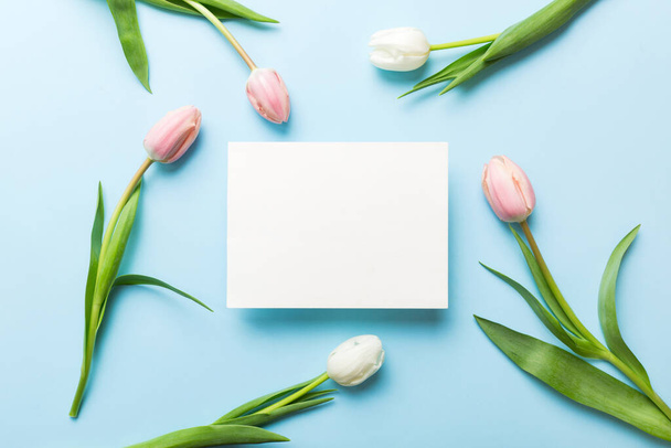 Samenstelling met blanco kaart en mooie bloemen tulp op gekleurde achtergrond. bovenaanzicht met ruimte voor u desing. - Foto, afbeelding